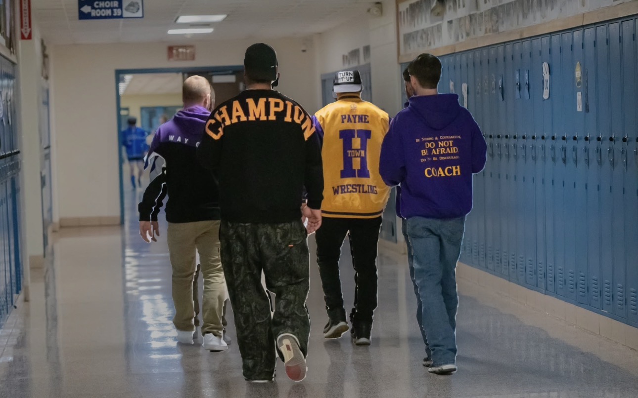 Black and white photograph of Payne H-Town wrestling coaches walking a school hallway